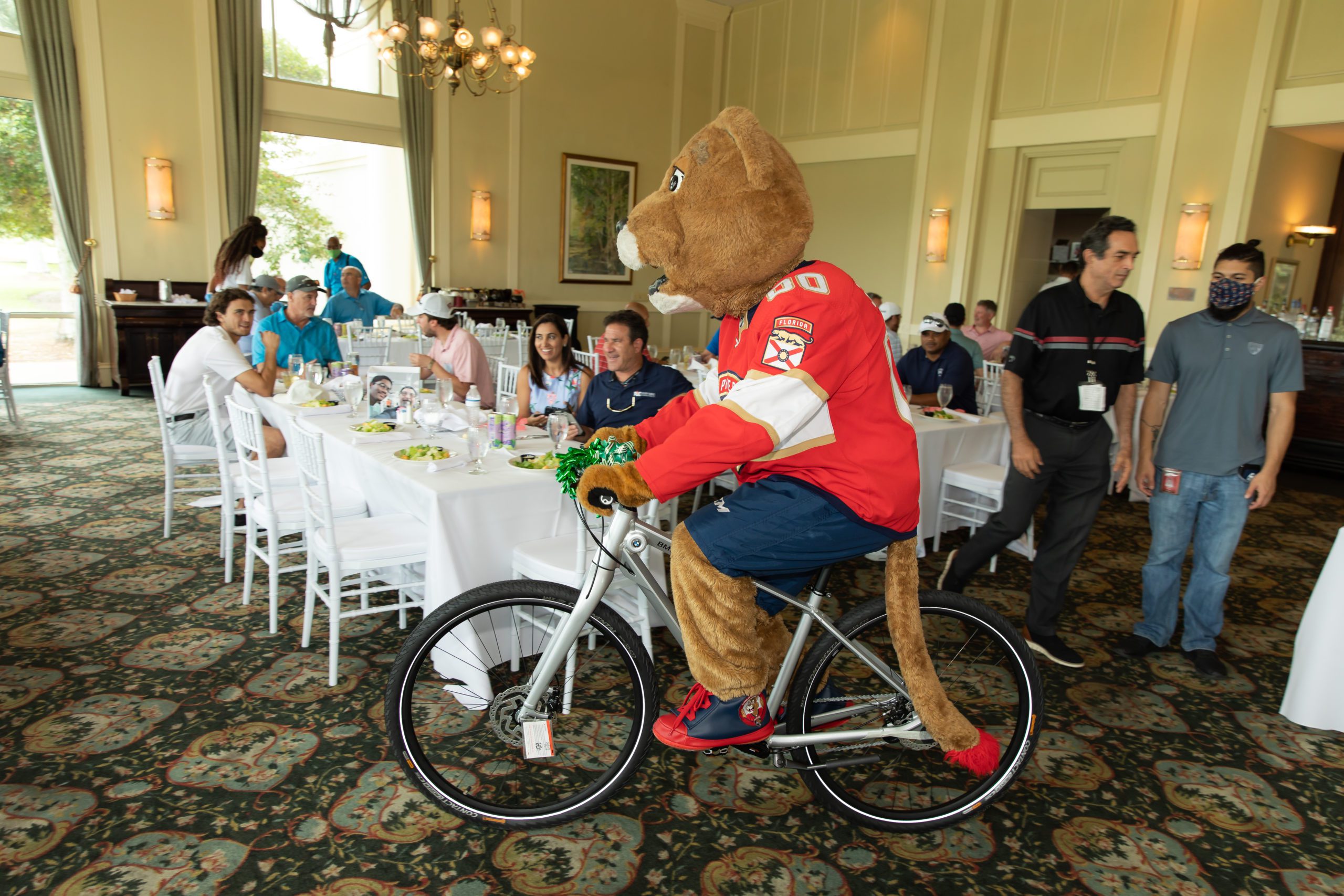 Stanley Panther mascot riding on a bike at a luncheon