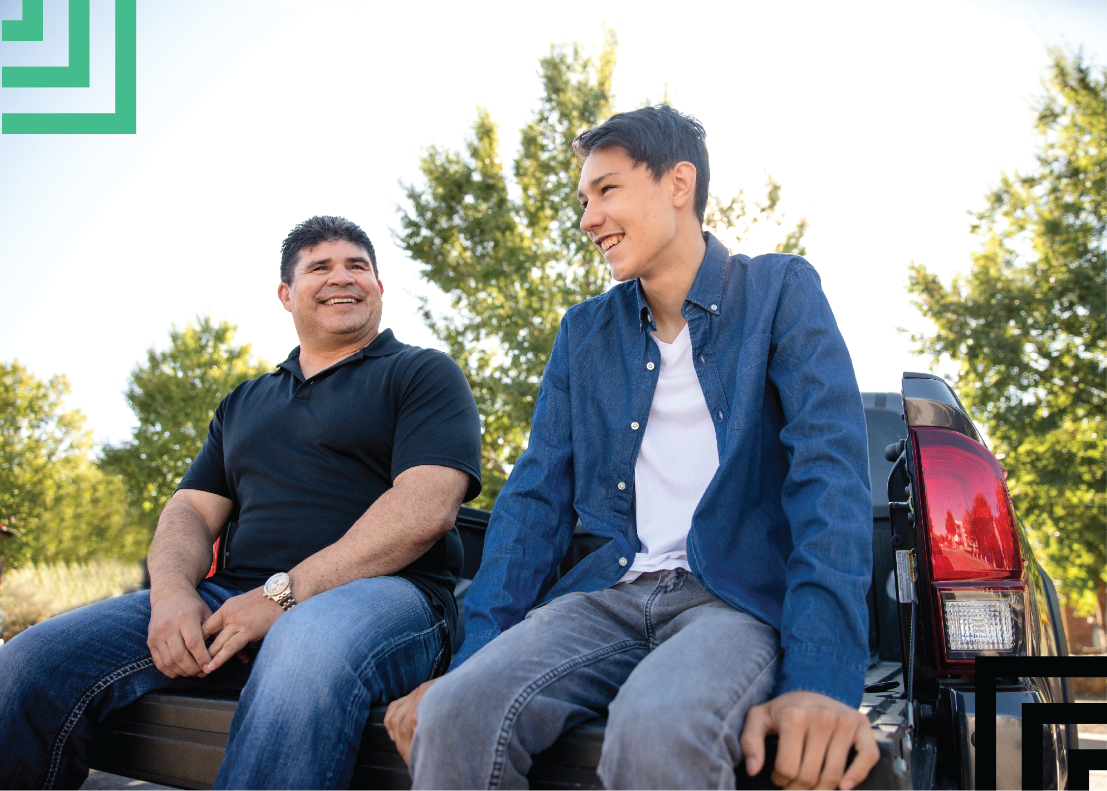 Big brother and little brother sitting on the bed of a truck smiling