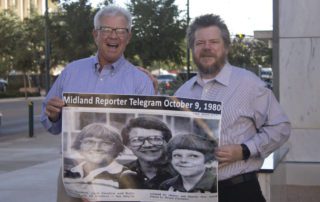 Two men smiling and holding a photo of themselves in 1980