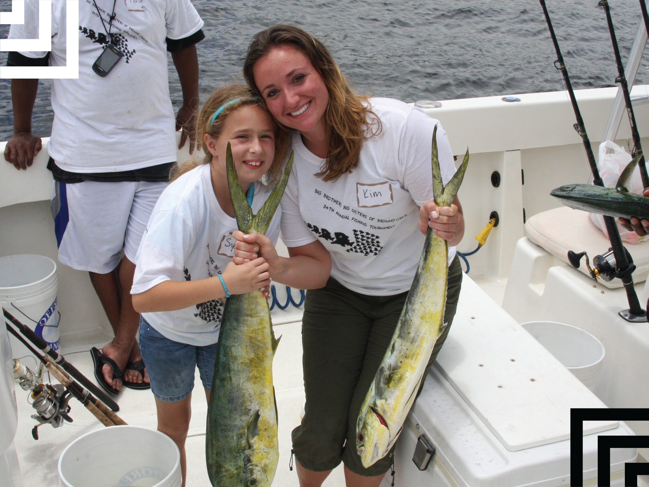 Big sister and little sister holding fish and smiling on a boat